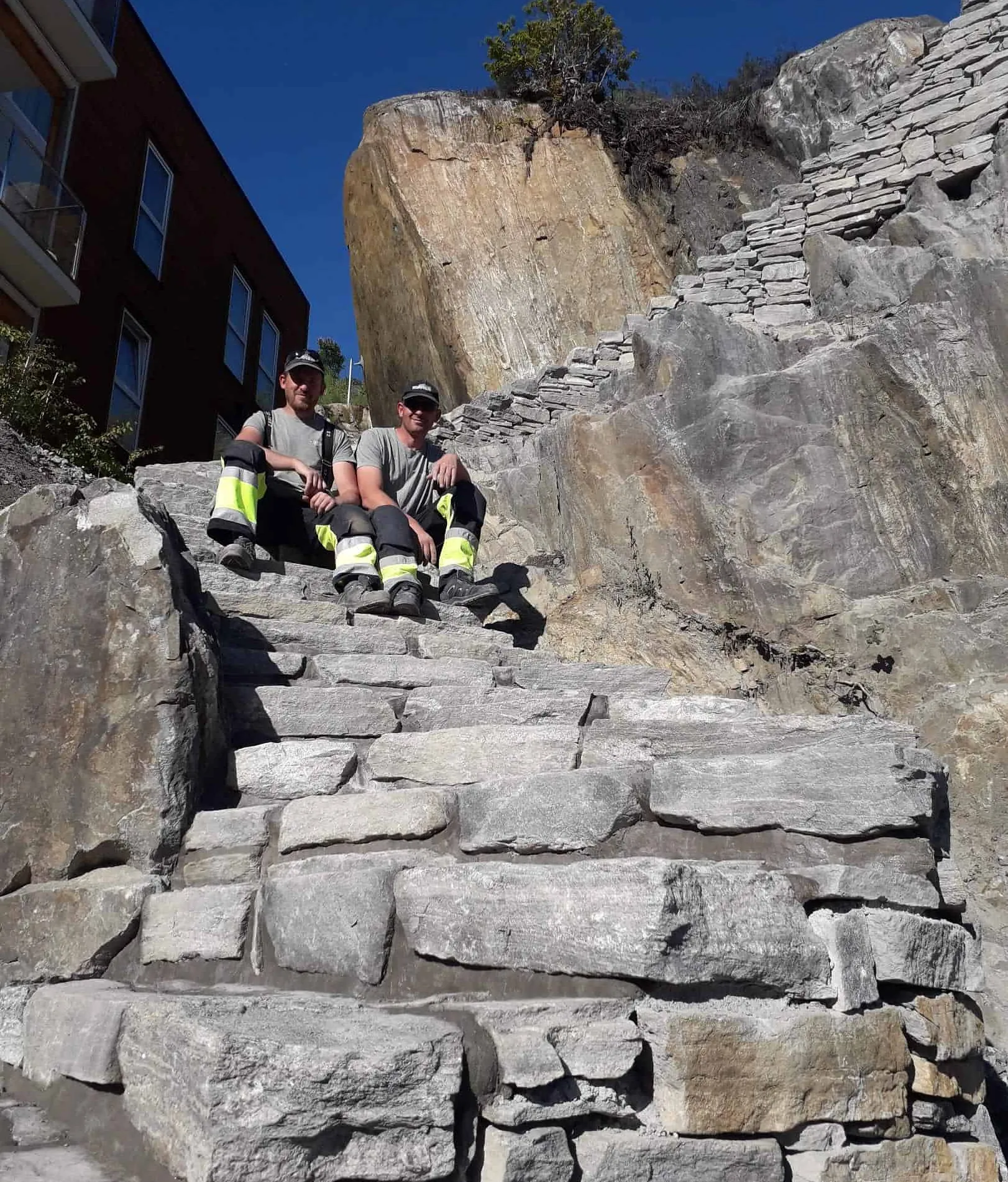 To personer sitter på steintrapp i et fjellområde