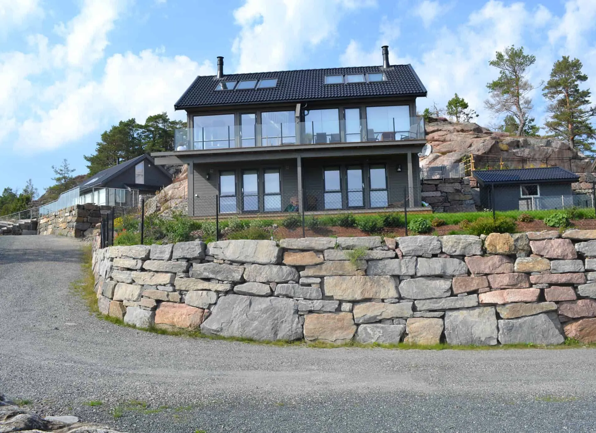 Moderne hus med stor steinmur og inngjerdet hage