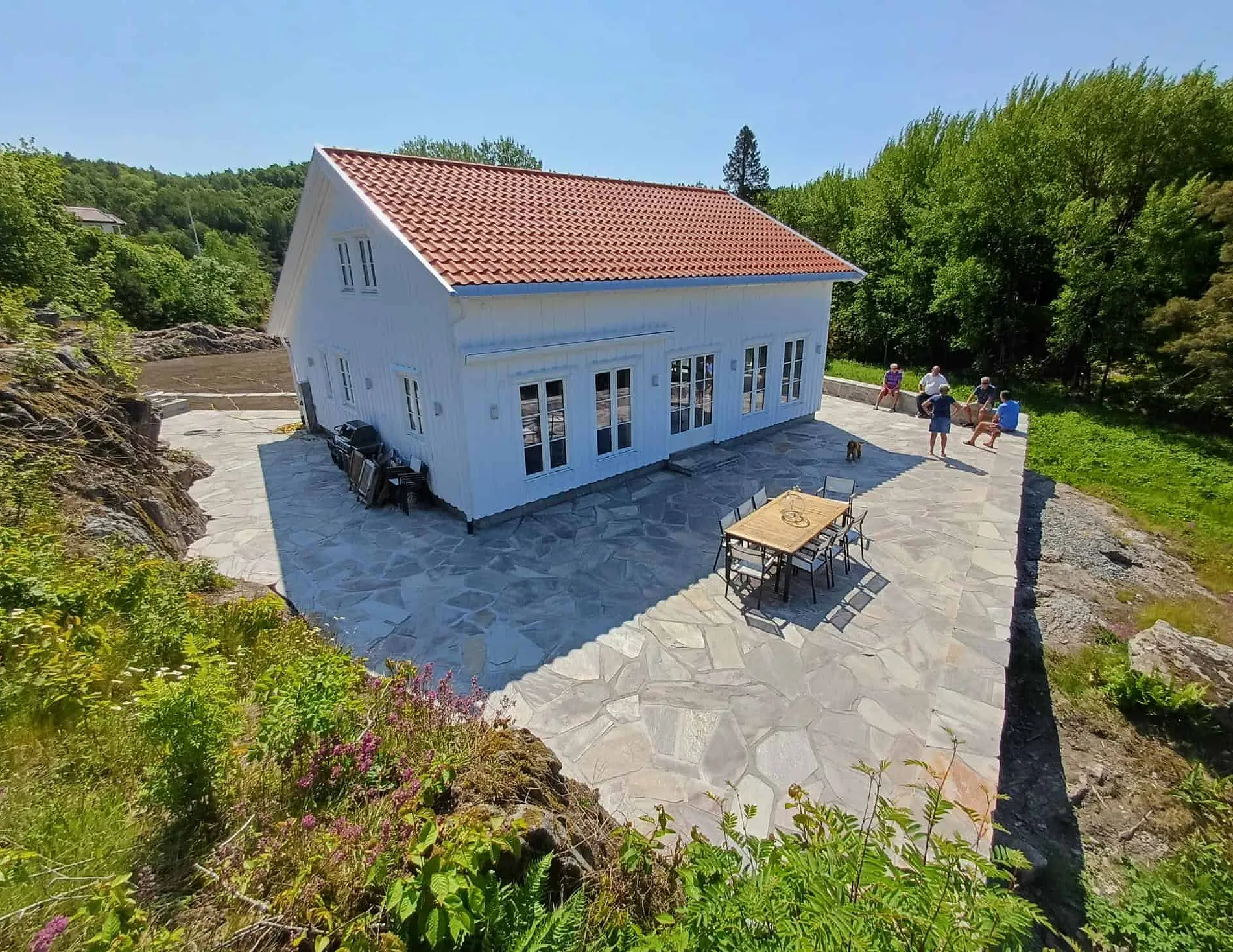 Hvit bygning med uteplass og natursteinsdekke rundt